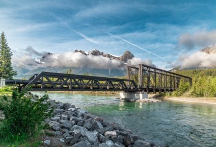 the Canmore Engine Bridge across the Bow River in the summer with mountains in the background