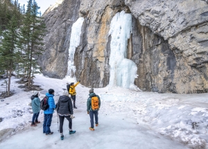 a tour group on a grotto canyon ice walk looking at a frozen waterfall