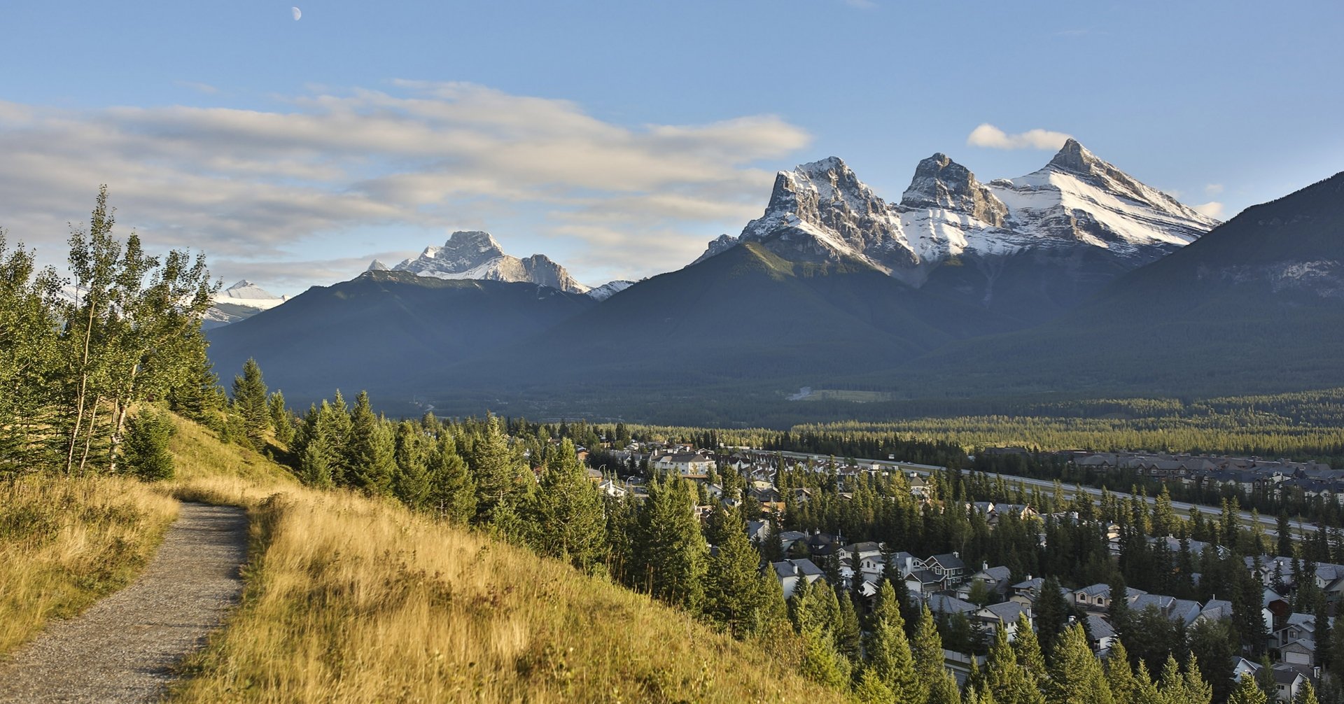 a pathway overlooking the town of Canmore and the three sisters mountains