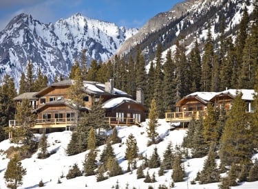 a photo of Mount Engadine Lodge nestled in the forest and mountain ranges in the winter