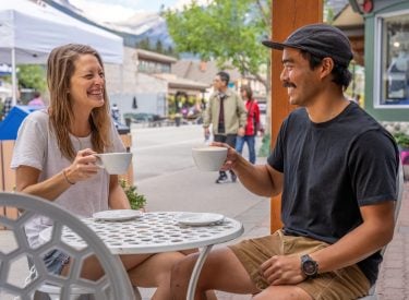two people enjoying coffee on the outdoor patio at eclipse coffee roastery on canmore's main street