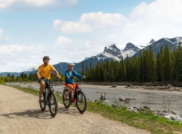 two people biking along the bow river in the summer