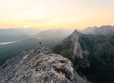 a person standing at the top of a summit at sunrise