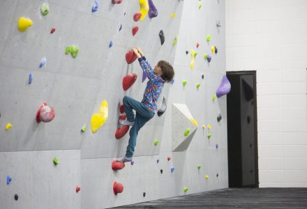 a boy climbing on the boudering walls at canmore climbing gym