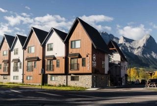 a landscape photo of Basecamp Resorts in the fall with blue skies and Ha Ling Peak in the background