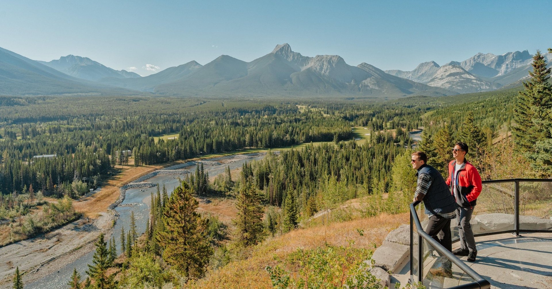 two people at a viewpoint in Kananaskis gazing out into nature with mountains and a river in the background