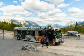 a couple offloading a Roam Transit bus at Grassi Lakes Trailhead