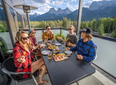 a group of people dining outside on the cangolf patio with the three sisters mountains in the background
