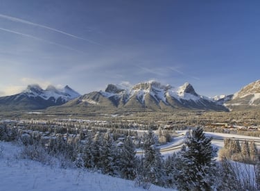 a landscape shot of mountain ranges above the town of canmore in the winter