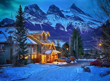 Winter night exterior of the Creekside Villa with the Three Sisters Mountains in the background