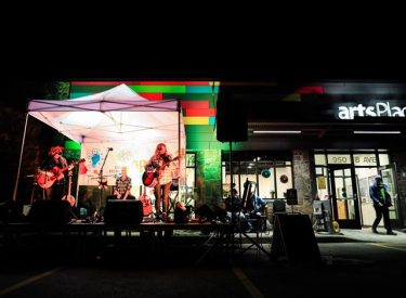 An artist singing during a concert at the artsPlace Canmore, on an outside stage.
