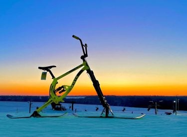 a photo of an electric ski bike take on a ski hill at sunset