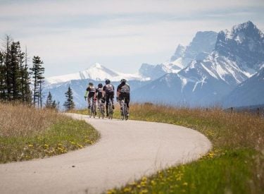 a group of cylists pedaling along Legacy trail with the mountains in the background