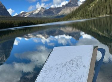 a person sketching the mountain scenery