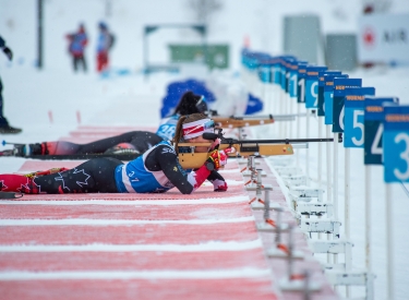 two biathaletes shooting guns at the shooting range
