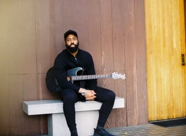 Portrait of Canadian singer-songwriter AHI with his guitar
